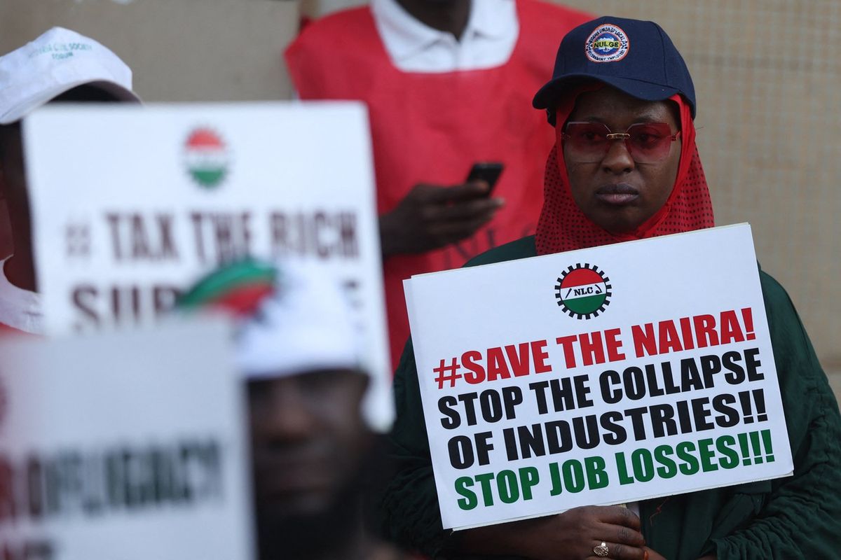 A woman holds a placard that reads “Save The Naira, Stop The Collapse Of Industries!! Stop Job Losses!!!” during a protest against the soaring cost of living in Abuja on February 27, 2024