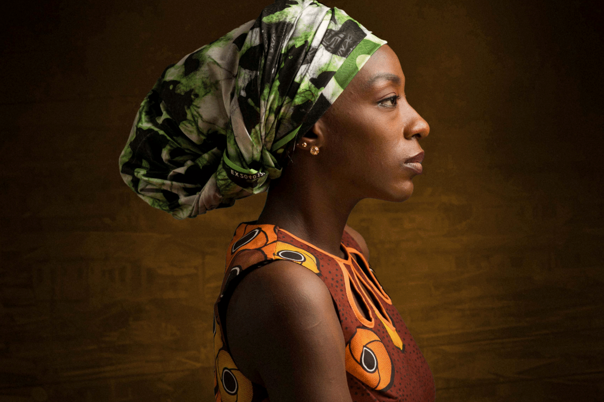 An image of a woman wearing a green wrapped headdress, side profile