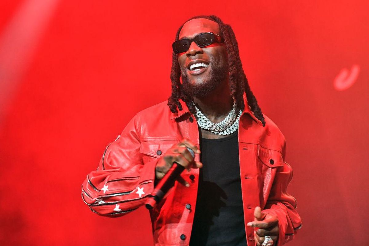 burna boy wearing red onstage performing and smiling